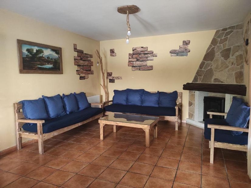 Casa Rural los Alisos sala de estar con sus sillones mesa central y chimenea